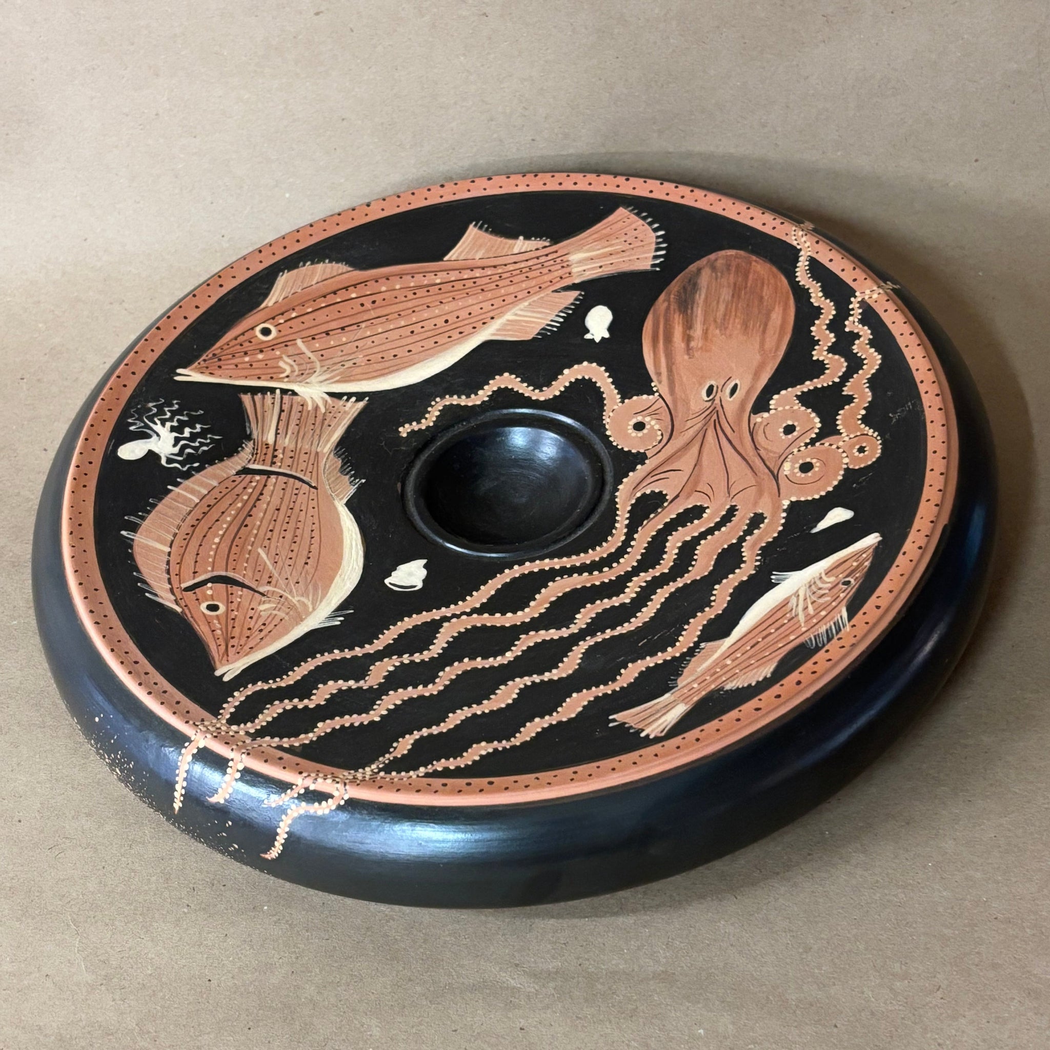 Decorative plate with fish and octopus design on a beige background