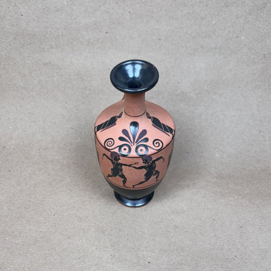 Small decorative vase with black and red designs on a beige background
