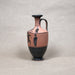 Ceramic vase with black and red design on a gray background