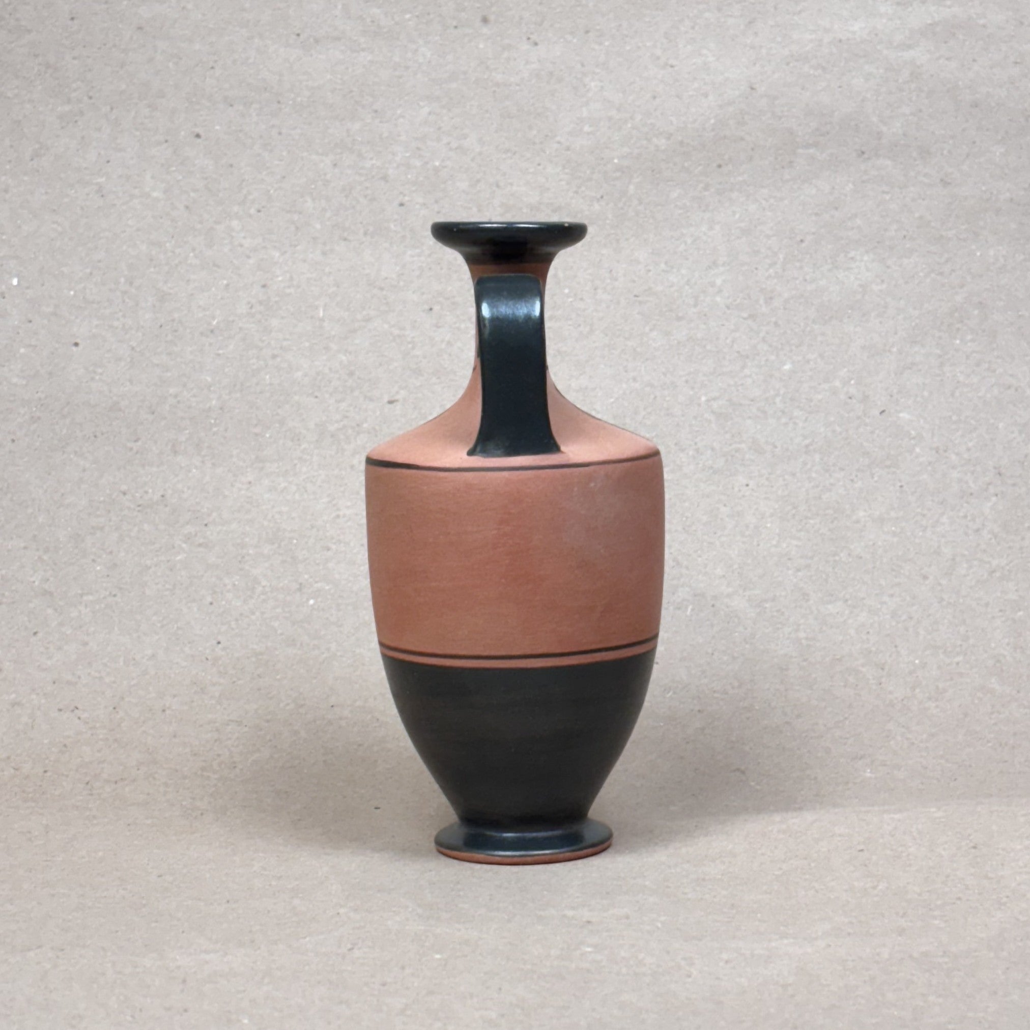 Ceramic vase with black and brown design on a textured beige background