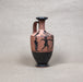 Ceramic vase with black and red designs on a gray background