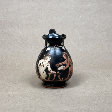 Small black vase with red and white figures on a gray background