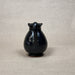 Black ceramic pitcher on a beige background
