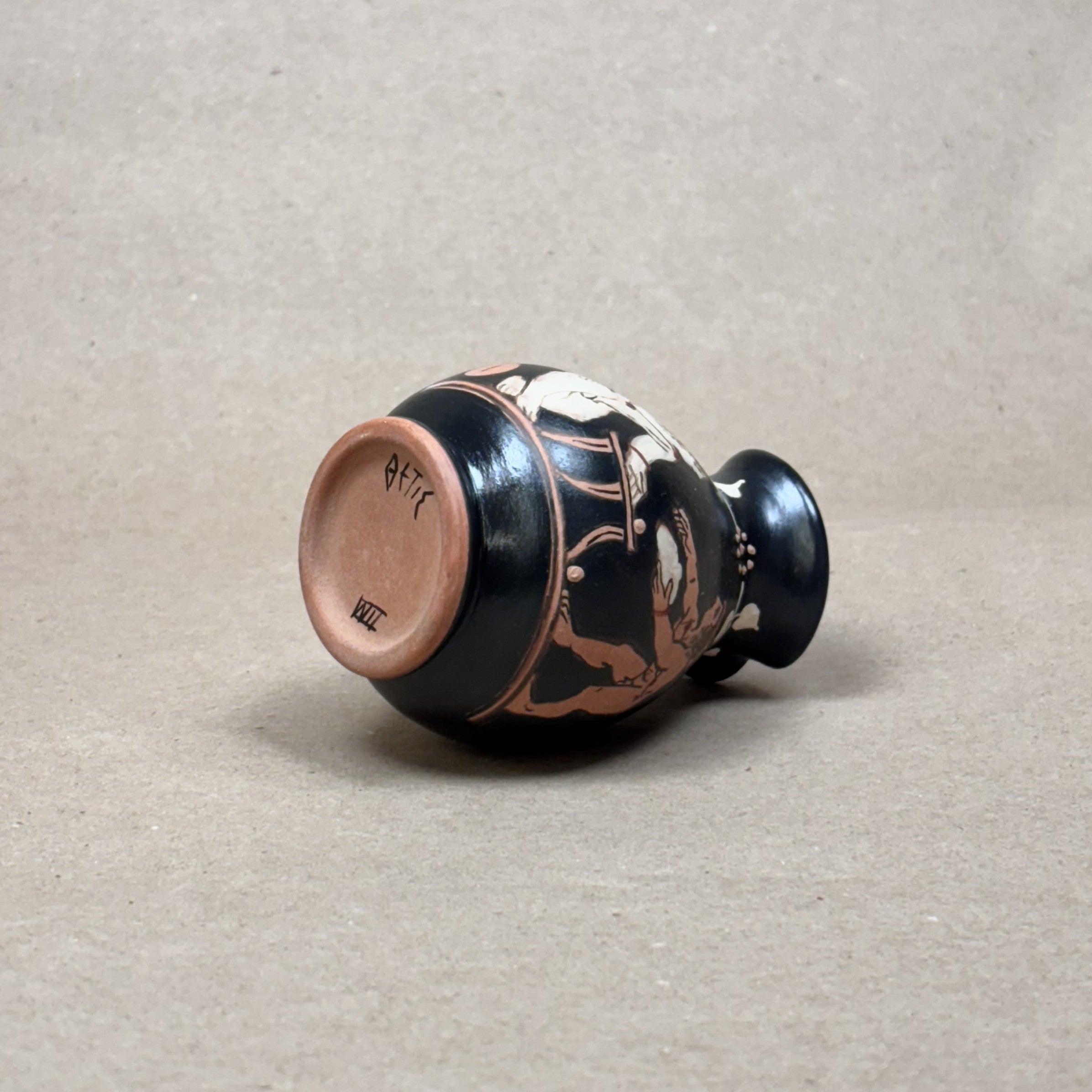 Ceramic vase with black and red design on a beige background