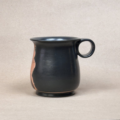 Black ceramic mug with a handle on a beige background
