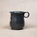 Black ceramic mug with a handle on a beige background
