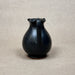Black ceramic pitcher on a beige background