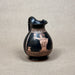 Black ceramic pitcher with red decorative patterns on a gray background
