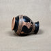 Black ceramic vase with decorative copper patterns on a beige background