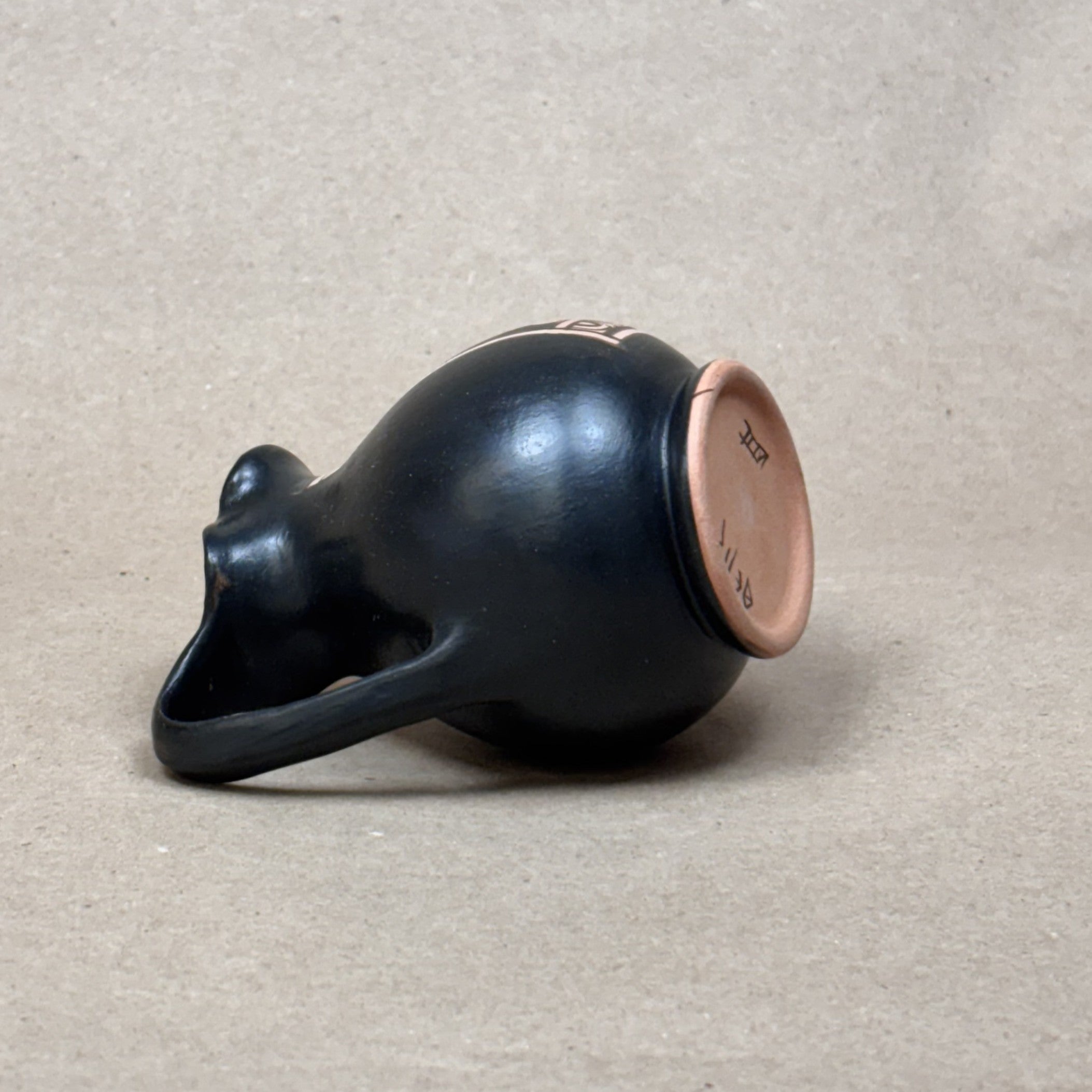 Black ceramic jar with a brown lid on a beige background
