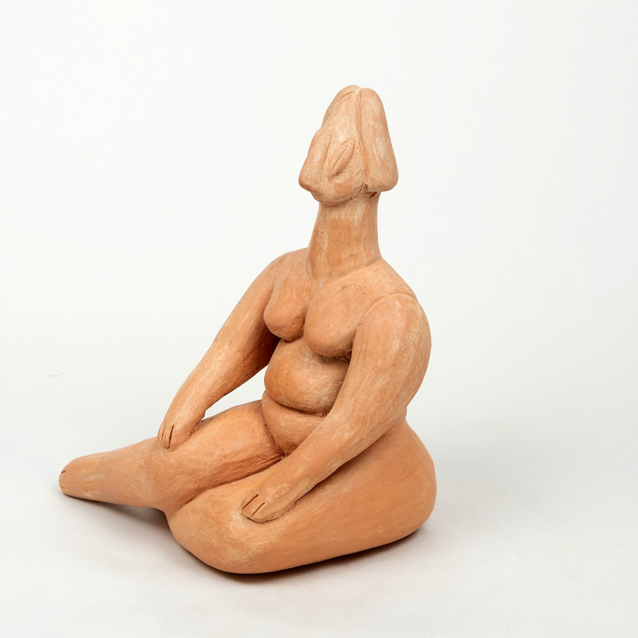 This image features a handmade clay figurine of a seated woman, inspired by a Middle Neolithic idol from around 5800–5300 BCE. The figurine, crafted by Angeliki Dervenioti in 2020, is a modern reinterpretation of the iconic Neolithic "Venus" figure.