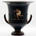 A black-glazed ceramic krater with a comic actor depicted running with cakes and fruits spilling from his cloak, and a woman standing in a near frontal pose to the left.