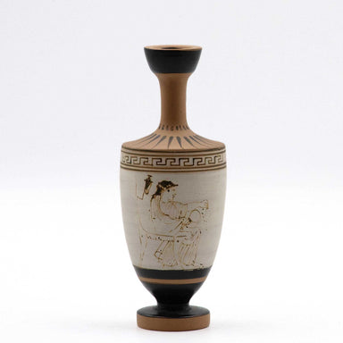 This image features a meticulously crafted white lekythos, a type of oil flask, adorned with a beautifully diluted clay-paint that produces a striking gold-like outline upon firing. The scene depicts a seated woman, dressed in a chiton and himation, engaging with a mirror and a wreath.
