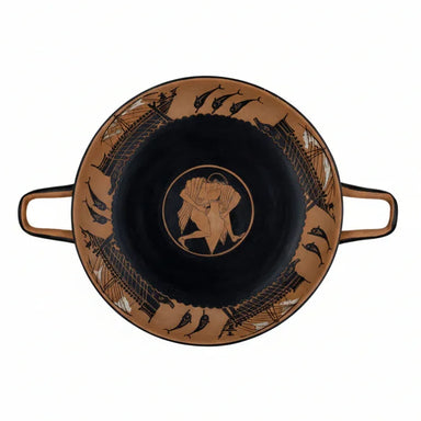 A black and red figure Kylix with youth lifting a amphora and galleys sailing on waves, with a wreath and a red band on the lip.