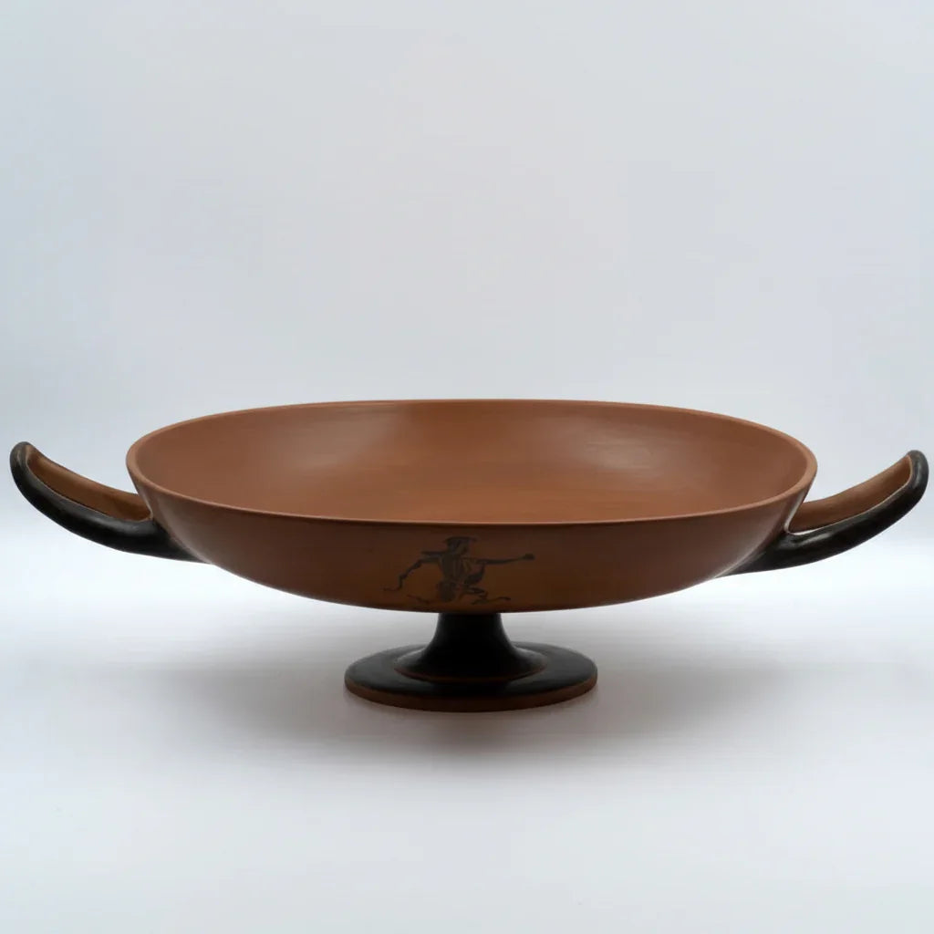 A large coral red ceramic decorative bowl with a black base, displayed against a plain background.