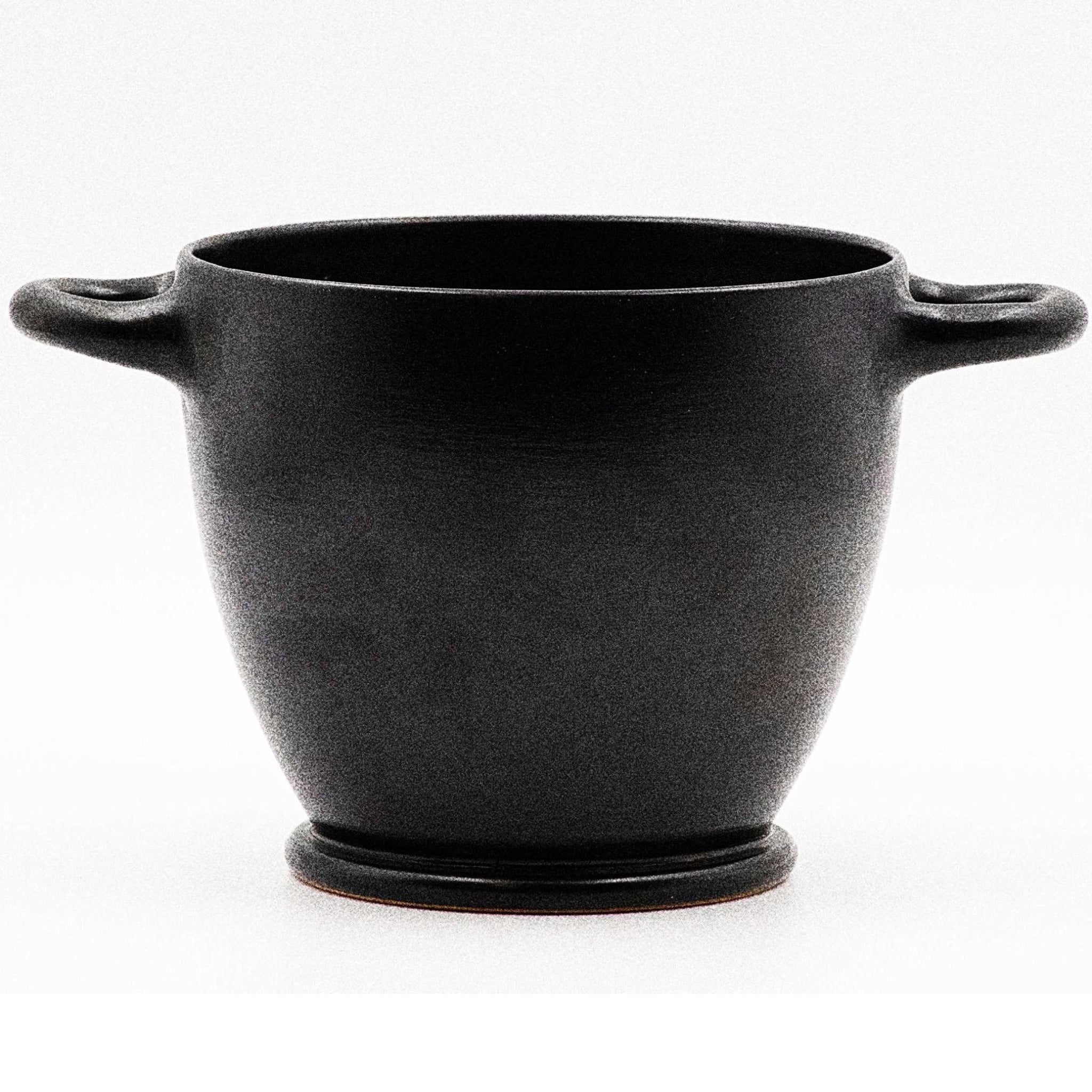 A black glazed ceramic skyphos with a visible orange rim.