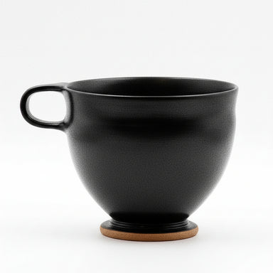 A black glazed ceramic bowl with a handle.