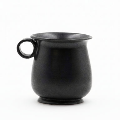 A black glazed ceramic mug with a tulip shape and a handle on the side.