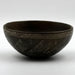 A dark-colored ceramic incised bowl with a geometric pattern on the interior.