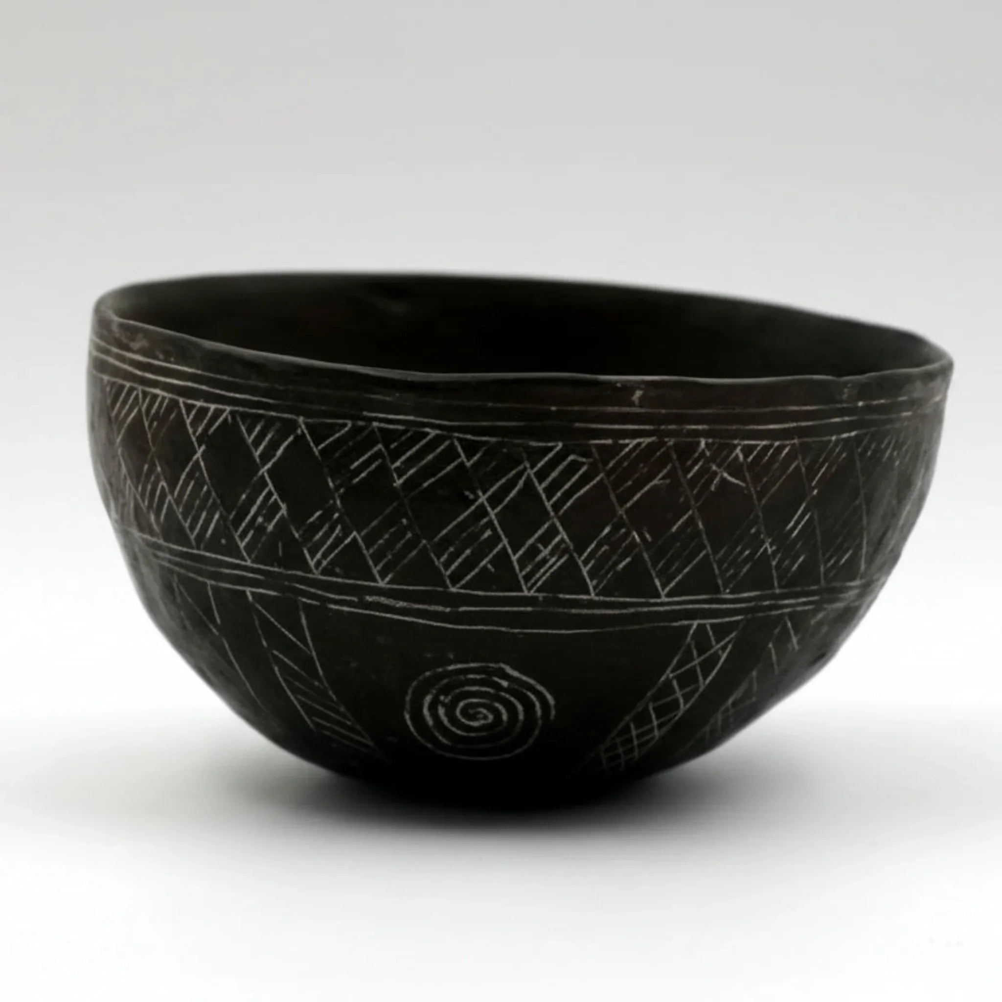 A Cypriot dark incised bowl with a geometric pattern, displayed against a white background.