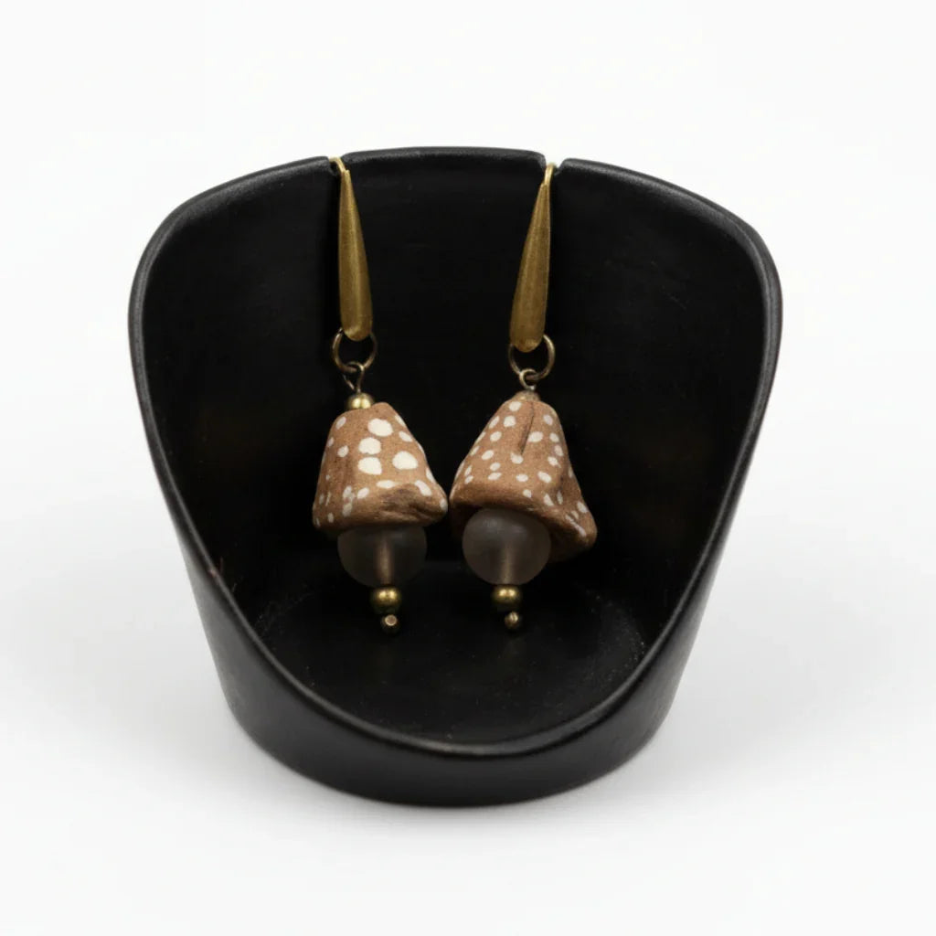 A pair of dot funnel bead and glass drop earrings displayed in a black setting, with gold-colored accents and drops.