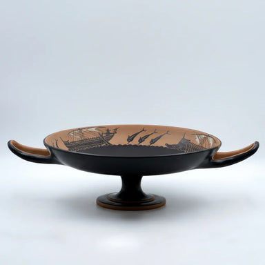 Handmade ancient Greek ceramic kylix with black-figure ship and dolphin design on pedestal