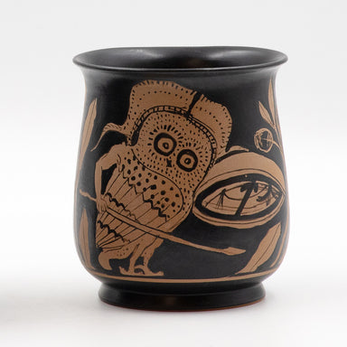 A black ceramic mug with a red-Figure depiction of an armed owl design, inspired by a classical artwork.