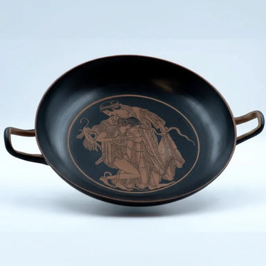 An ancient Greek style kylix with a depiction of a mythological scene in red on a black background.