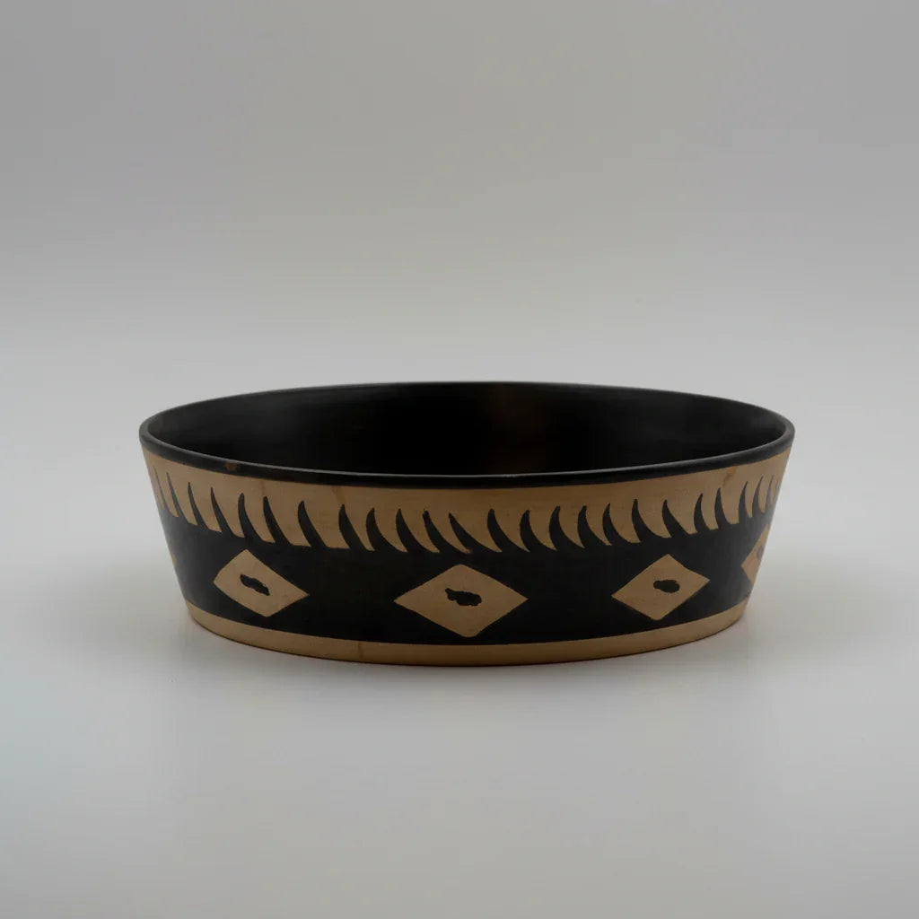 A shallow, large bowl with black and beige geometric patterns