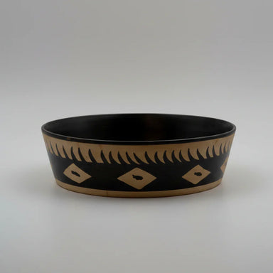 A shallow, large bowl with black and beige geometric patterns