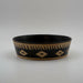 A shallow, large bowl with black and beige geometric patterns
