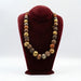 A ceramic bead necklace displayed on a red velvet stand, featuring a variety of earthy tones.
