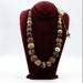 A beaded necklace with a variety of ceramic beads in different shapes and colors displayed on a mannequin bust.