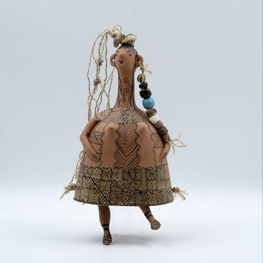 Textile art doll with patterns and beads on a light gray background