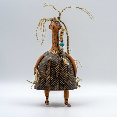 A bell-shaped plangona doll with painted decoration, featuring a neck, head, and hands attached to the body. The doll is adorned with polychrome threads, wool, and decorative beads.