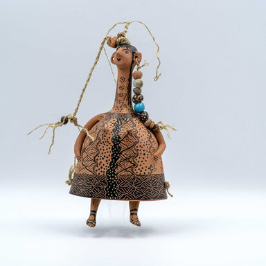 A bell-shaped plangona doll with a human-like face and neck, adorned with polychrome threads, wool, and ceramic beads, against a white background.