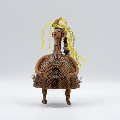 A bell-shaped ceramic doll with geometric patterns, a yellow hair accessory, and decorative beads.